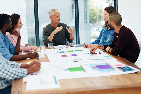 Person describing new product to five people at a business meeting