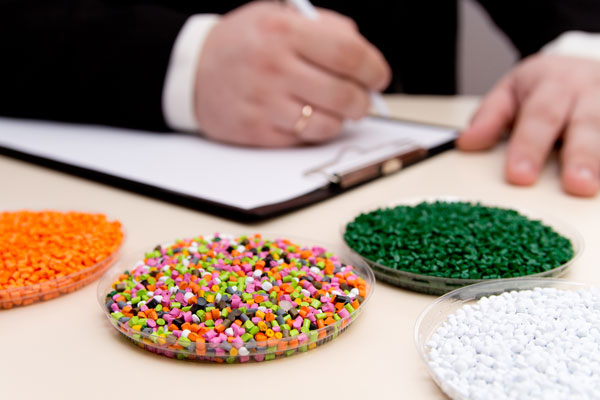 Man writing on piece of paper with trays of plastic molded pieces in front of him