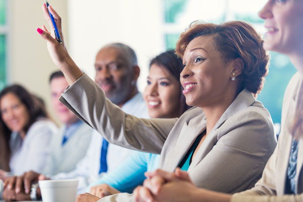 Woman raising hand in business meeting