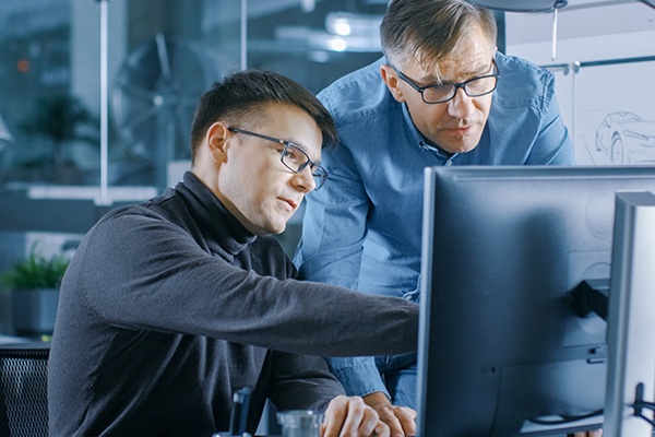 Plastic engineers around a computer discussing a project